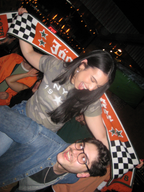 Two people posing with a large Jägermeister Racing scarf