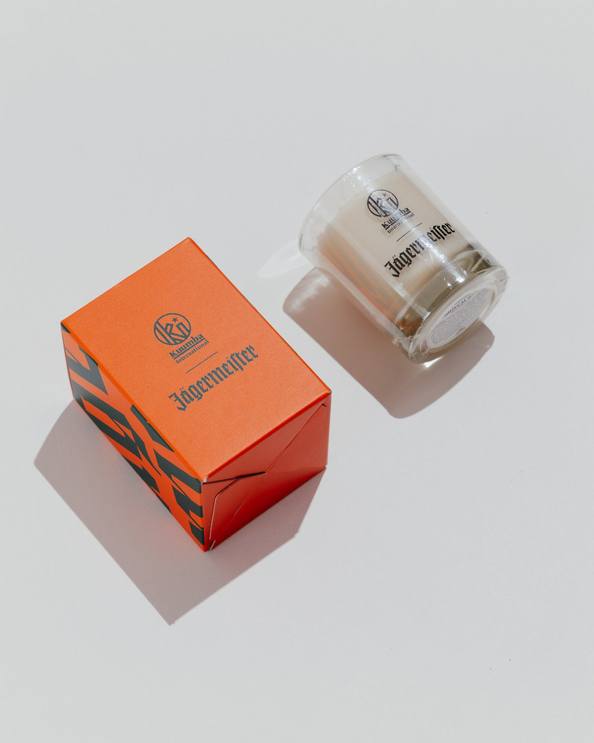 Jägermeister candle and orange box from the top on a light gray background