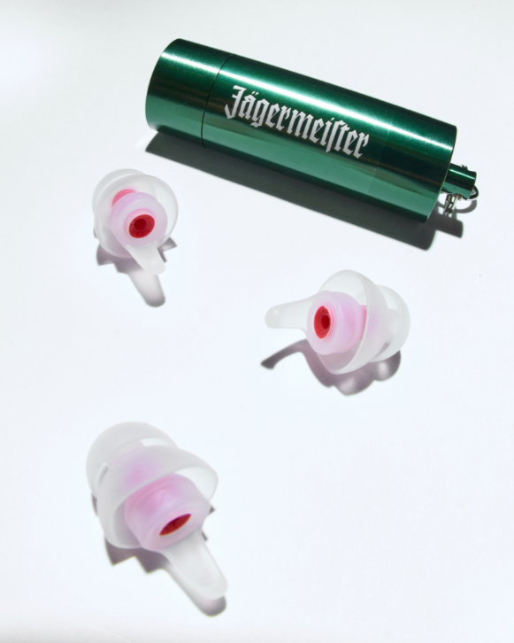 Green Jägermeister canister with three white earplugs on a white background