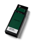 Frasco verde con la marca 'Jägermeister' en una caja negra etiquetada 'Pantone Herbal Green'.