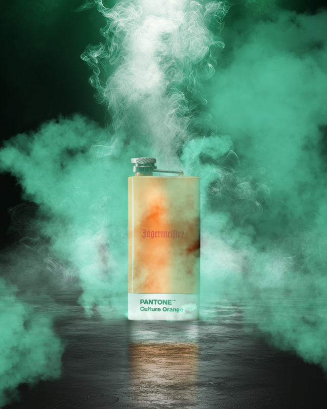 Botella de Jägermeister con etiqueta de color Pantone rodeada de humo verde sobre fondo oscuro
