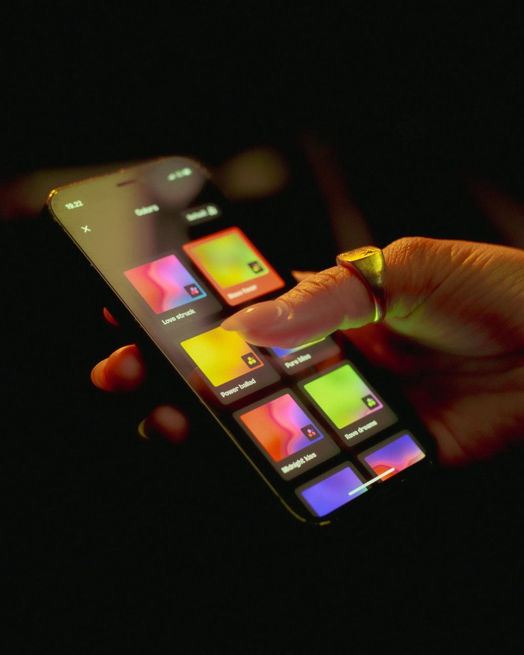 Hand interacting with a colorful digital device on a dark background