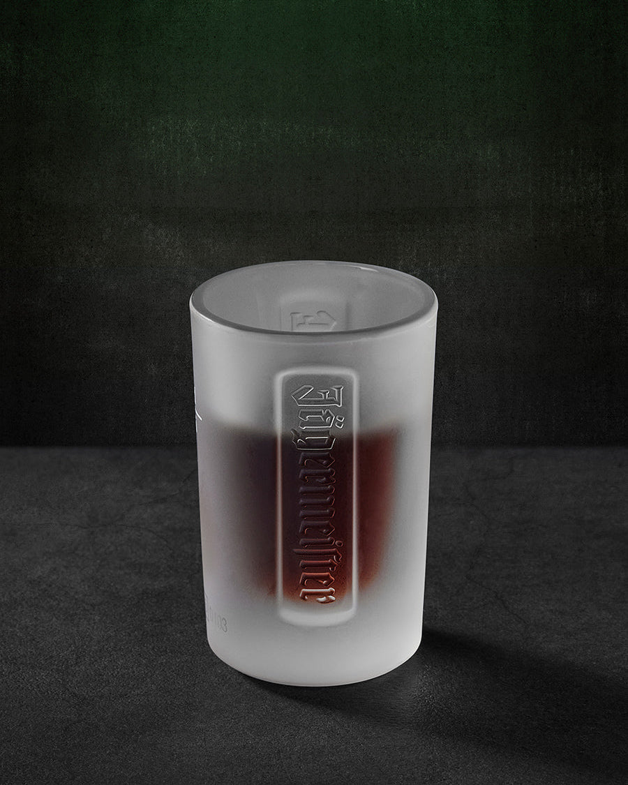 White Jägermeister shot glas with embossed Jägermeister wordmark
and liquid in it